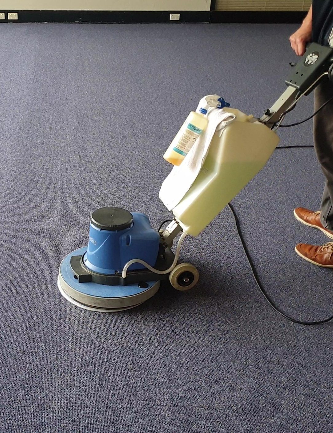 Our technician working the rotary scrubbing machine across blue broadloom in a Perth office, fitting the clean around the building.
