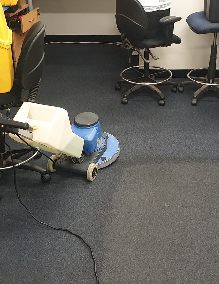 Carpet stains being cleaned with a scrubbing machine.